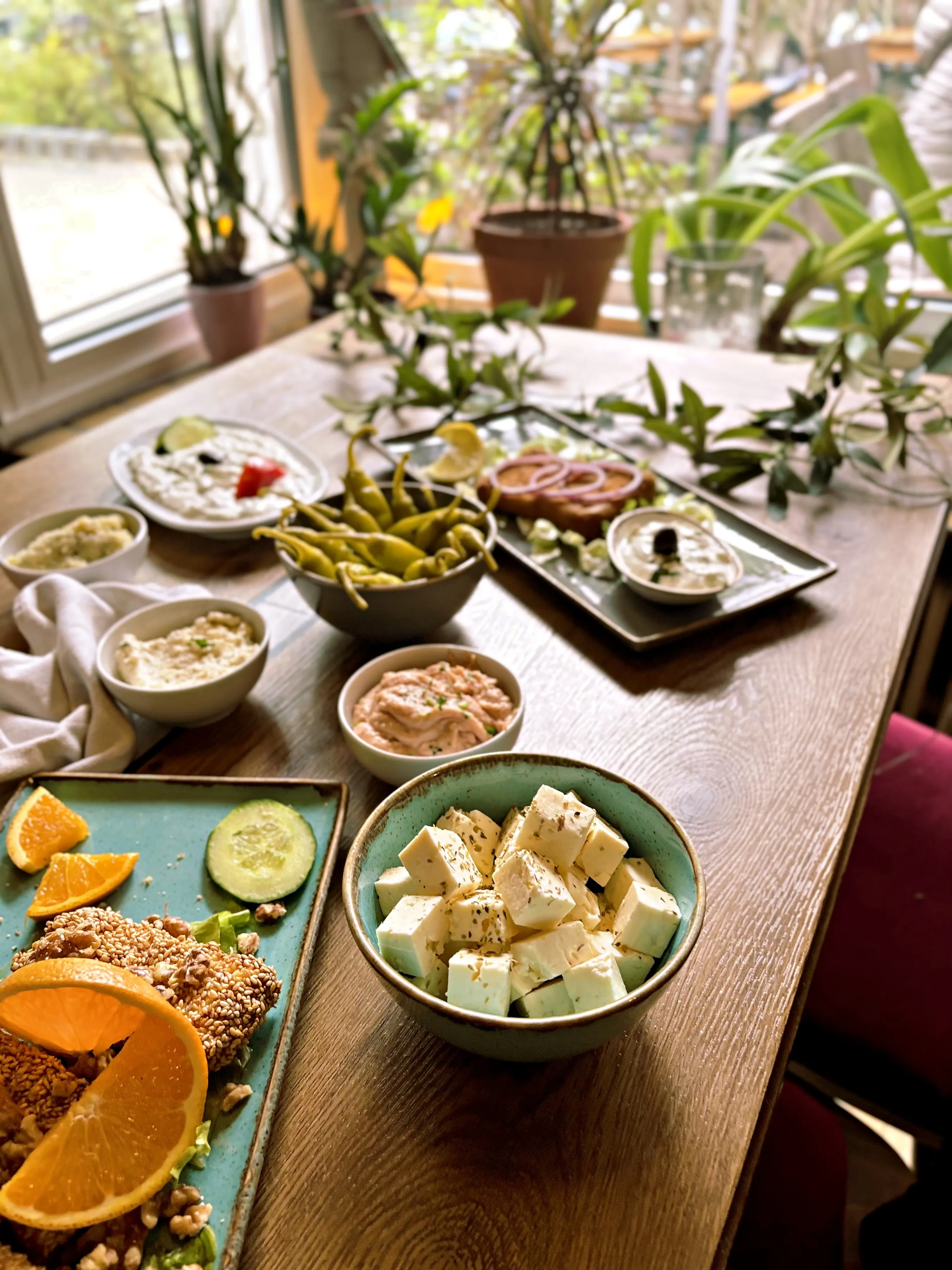 Tisch am Fenster mit Vorspeisen: Feta, Peperoni, Zaziki und Sesam-Saganaki