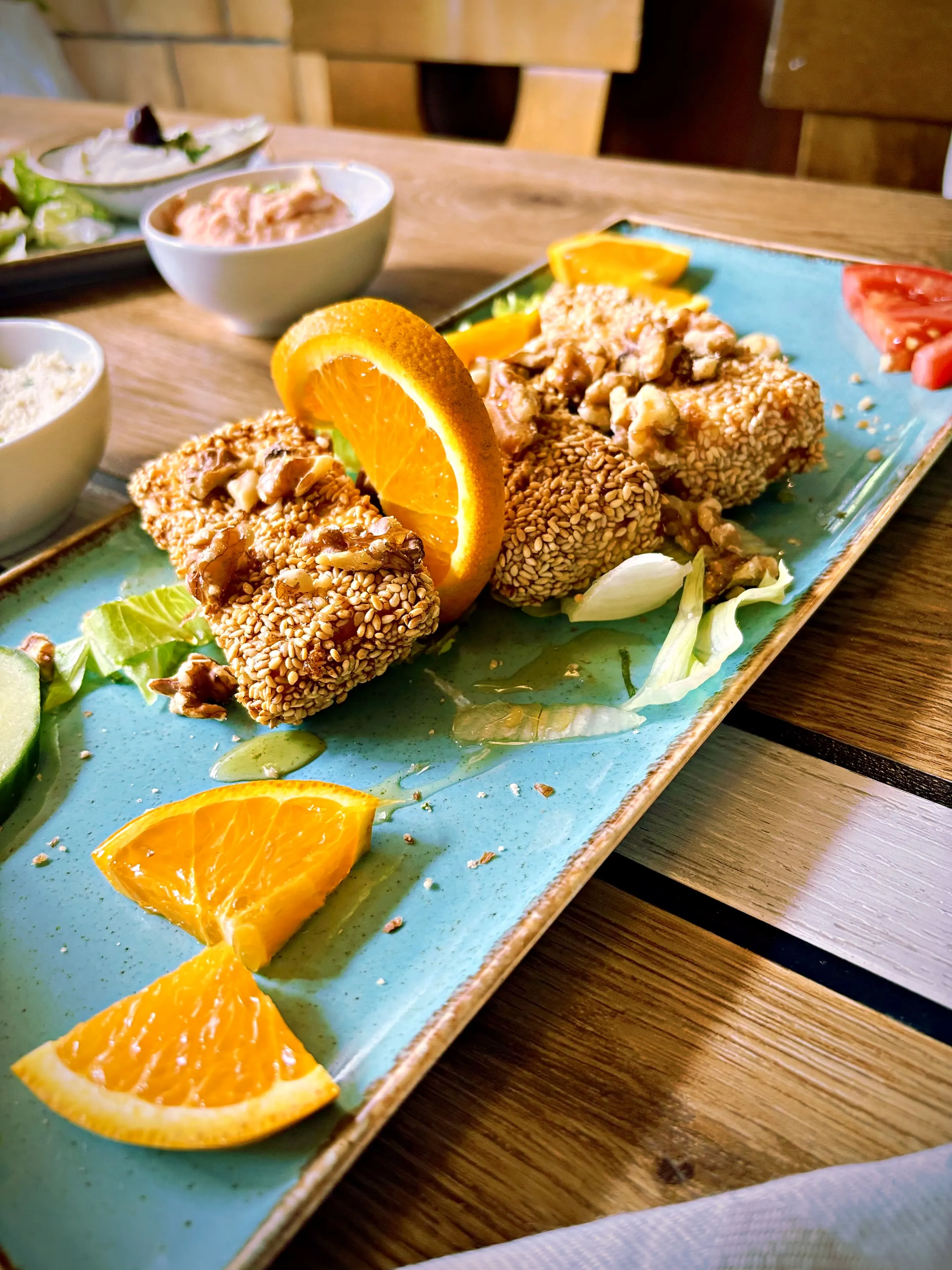 Sesam-Saganaki mit Honig und Orangenscheiben auf türkisfarbenem Teller