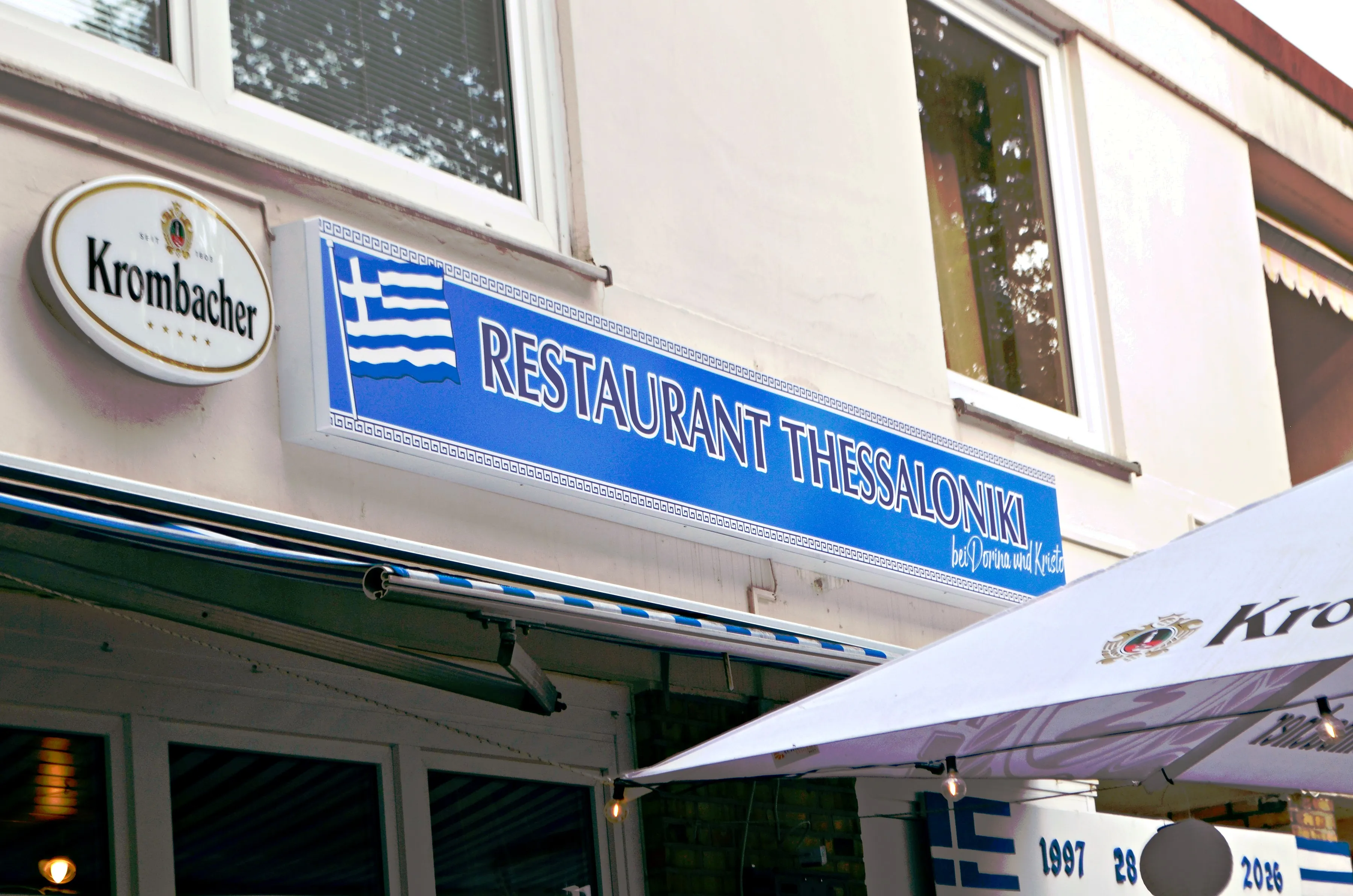 Die Fassade des Restaurants mit dem blau-weißen Schild Restaurant Thessaloniki